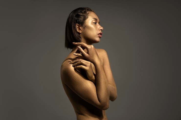 Foto gratuito mujer de plano medio posando con pintura corporal dorada