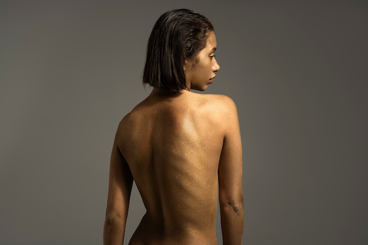 Foto gratuito mujer de plano medio posando con pintura corporal dorada