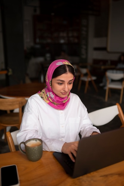 Foto gratuita mujer de plano medio trabajando con hijab en interiores