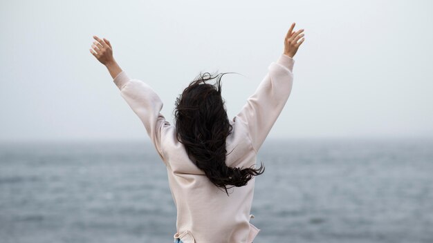 Mujer en la playa con los brazos alzados