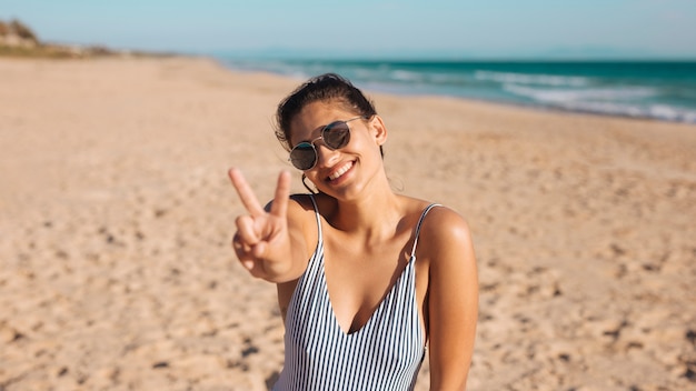 Mujer en la playa haciendo v suspiro