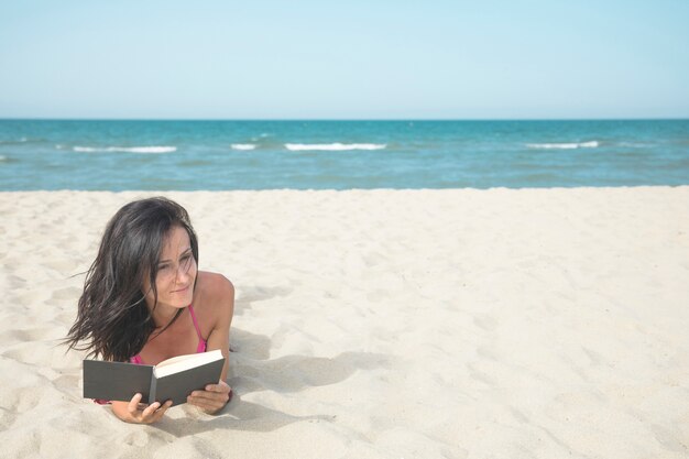 Mujer en la playa leyendo un libro