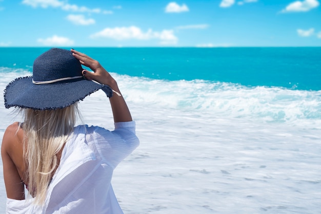 Mujer en la playa mirando hacia el mar disfrutando de las vacaciones de verano