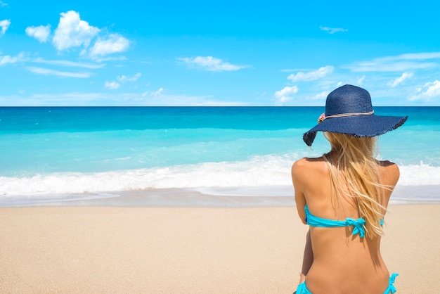 Mujer en la playa mirando hacia el mar disfrutando de las vacaciones de verano