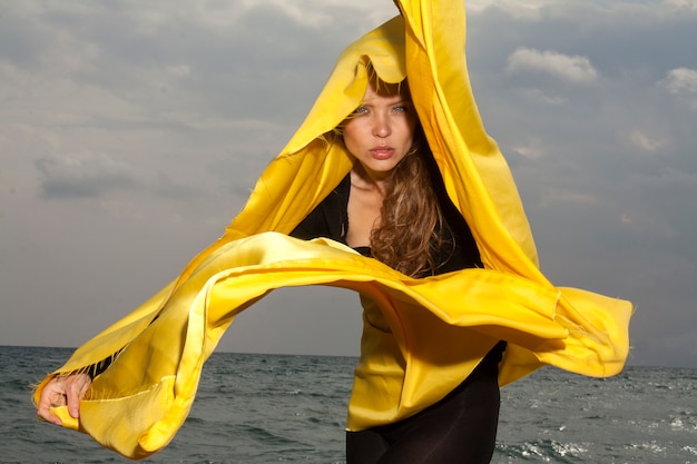 Mujer en la playa con pañuelo amarillo