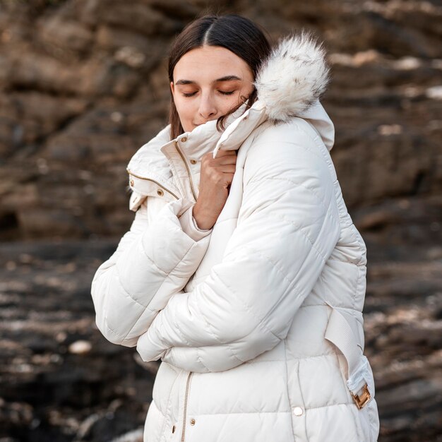 Mujer en la playa sola con chaqueta de invierno