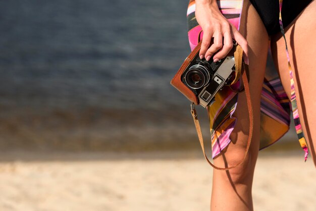 Mujer en la playa sosteniendo la cámara con espacio de copia