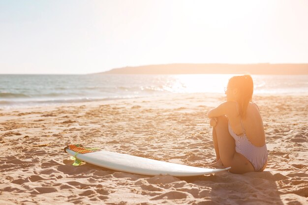 Mujer en la playa con tabla de surf