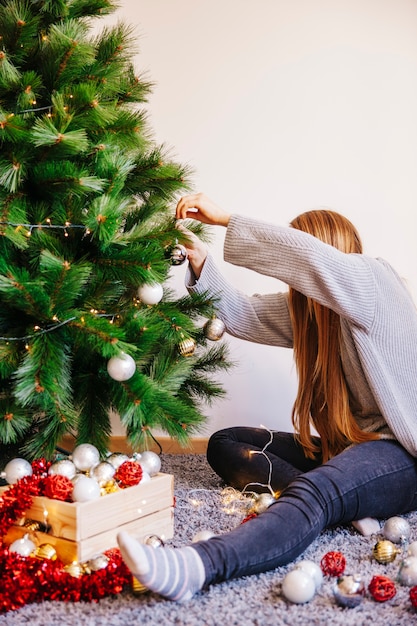 Mujer poniendo bolas en árbol de navidad