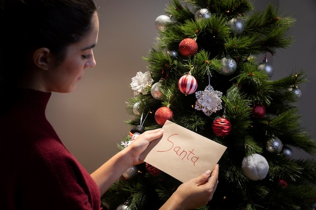 Mujer poniendo en la carta del árbol de navidad para santa claus