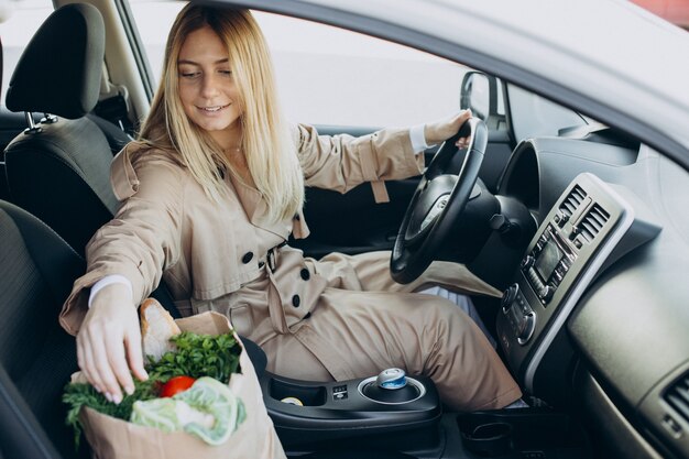 Mujer poniendo comida en una bolsa de compras en su coche