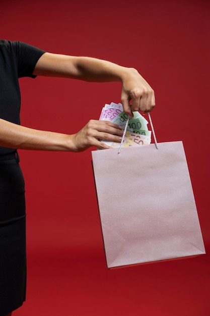 Mujer poniendo dinero en su bolsa de compras