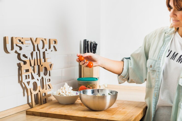 Foto gratuito mujer poniendo la ensalada en la cocina