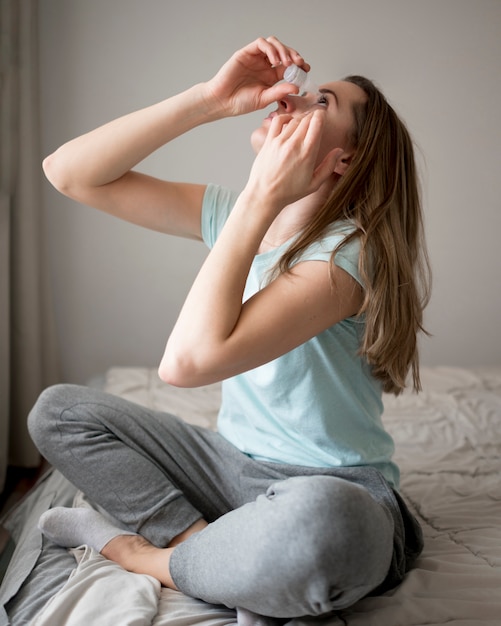 Mujer poniendo gotas para los ojos doloridos