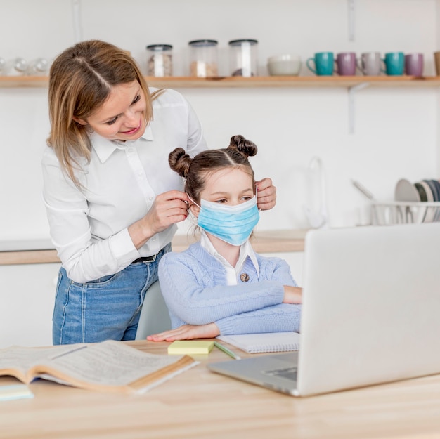 Foto gratuita mujer poniendo una máscara médica a su hija