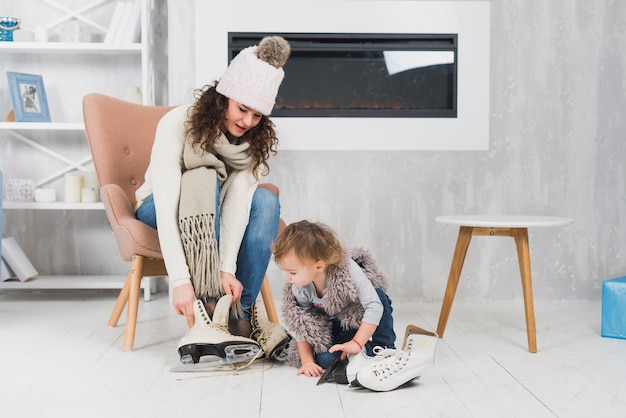 Foto gratuita mujer poniendo patines de hielo cerca de la niña