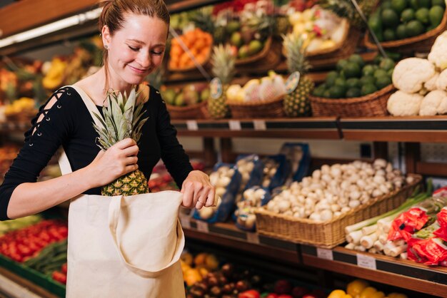 Mujer poniendo una piña en una bolsa