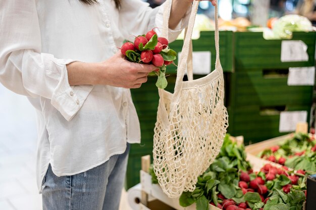 Mujer poniendo rábanos en bolsa reutilizable