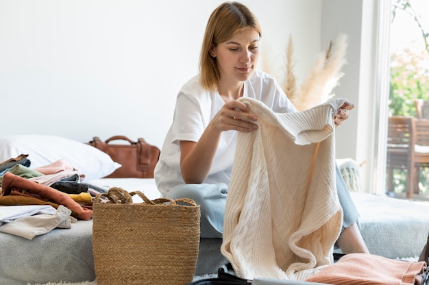 Foto gratuita mujer poniendo ropa en una maleta para las próximas vacaciones