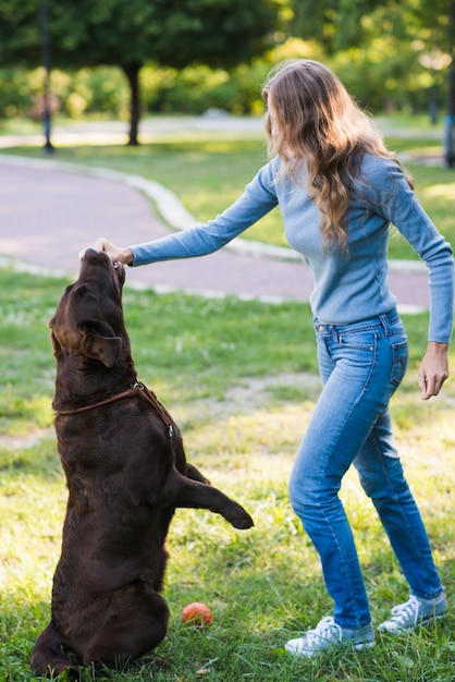 Mujer poniendo su mano en la boca del perro