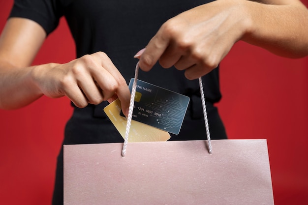 Mujer poniendo tarjeta de crédito en bolsa de compras