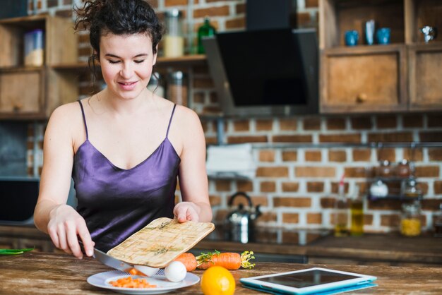 Mujer poniendo zanahoria en un plato