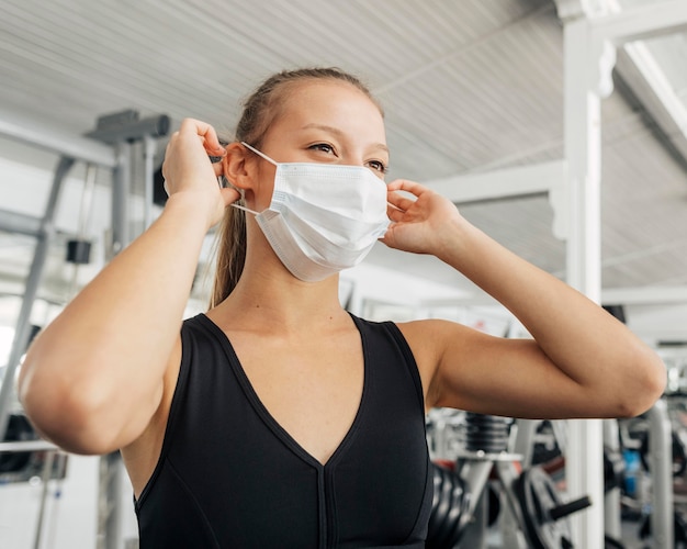 Mujer poniéndose su mascarilla médica en el gimnasio