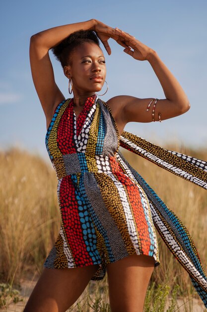 Mujer posando en un ambiente árido mientras usa ropa africana nativa