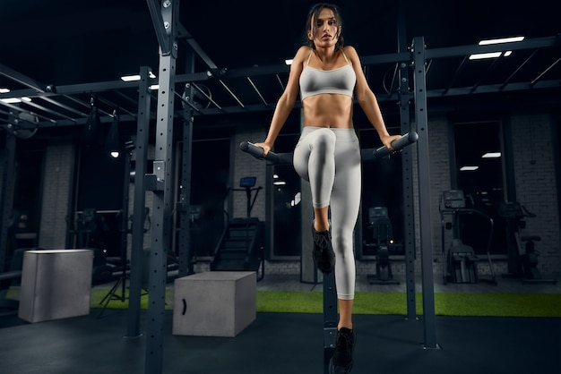 Mujer posando en barras paralelas en el gimnasio