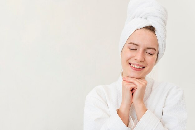Mujer posando en bata de baño y sonriendo con espacio de copia