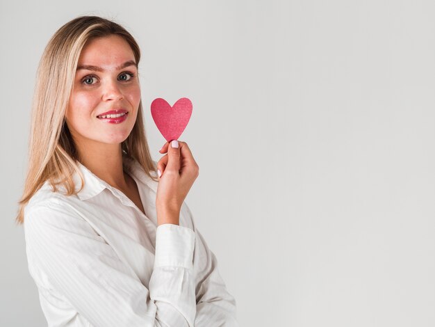 Mujer posando con corazón y copia espacio