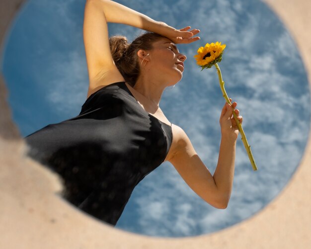 Mujer posando con espejo redondo y flor.