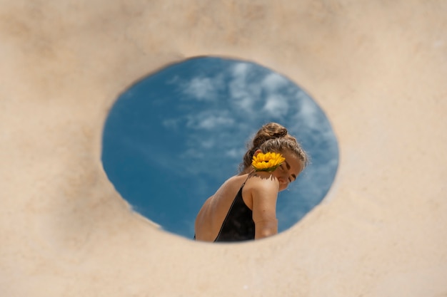 Mujer posando con espejo redondo y flor.