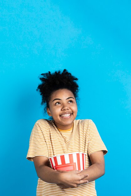 Mujer posando feliz mientras sostiene el cubo de palomitas de maíz