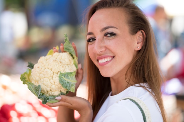 Mujer posando junto a una coliflor