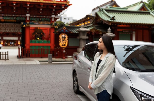 Mujer posando junto a su nuevo coche eléctrico