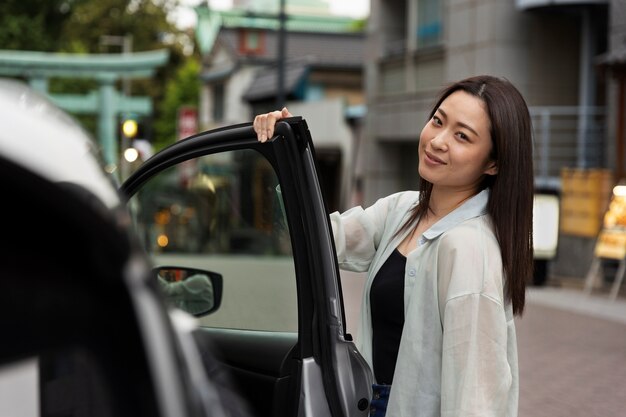 Mujer posando junto a su nuevo coche eléctrico