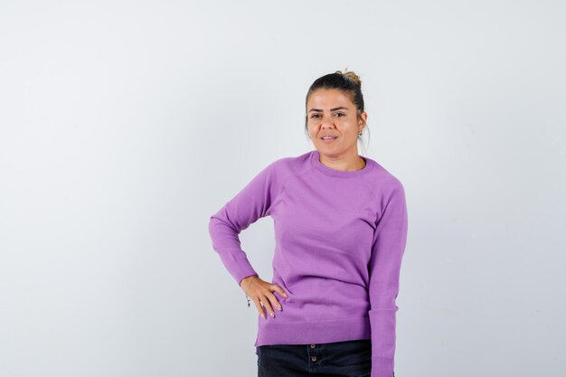 Mujer posando con la mano en la cintura en blusa de lana y aspecto encantador