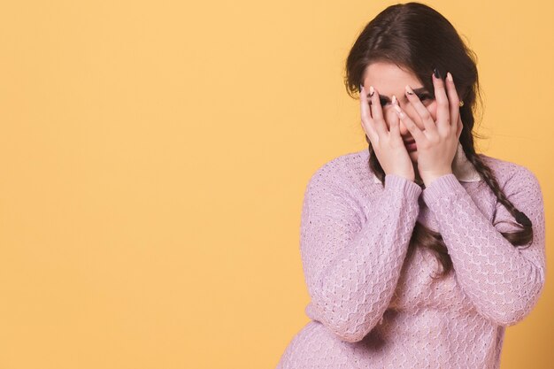 Mujer posando mientras se cubre la cara con las manos