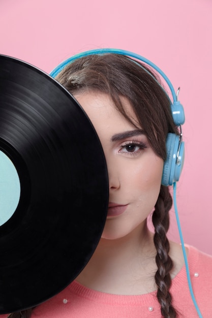 Mujer posando mientras cubre la mitad de la cara con disco de vinilo