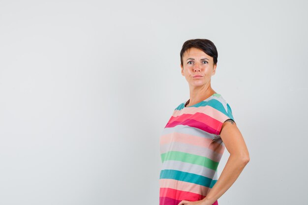 Mujer posando mientras está de pie en camiseta a rayas, pantalones y mirando disgustado