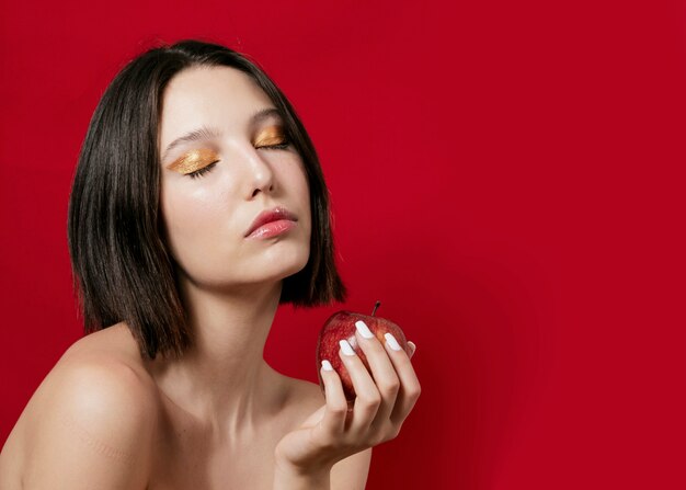 Mujer posando mientras sostiene una manzana