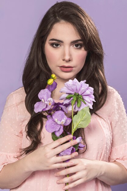 Mujer posando mientras sostiene un ramo de orquídeas y dalia