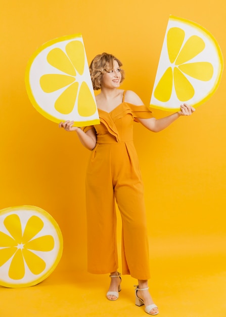 Mujer posando mientras sostiene rodajas de limón decoraciones