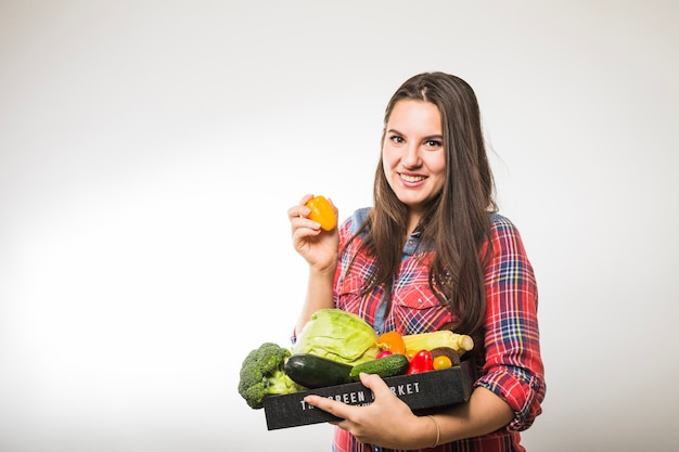 Mujer posando con pimiento y verduras