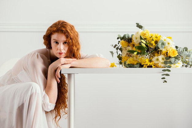 Mujer posando con ramo de flores de primavera sobre la mesa