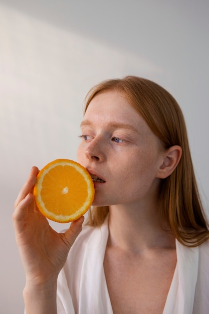 Mujer posando con rodaja de naranja tiro medio