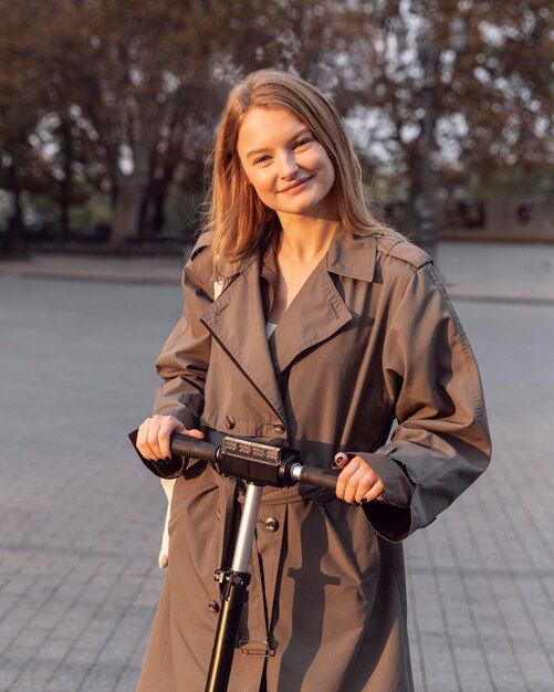 Mujer posando con su scooter eléctrico en la ciudad