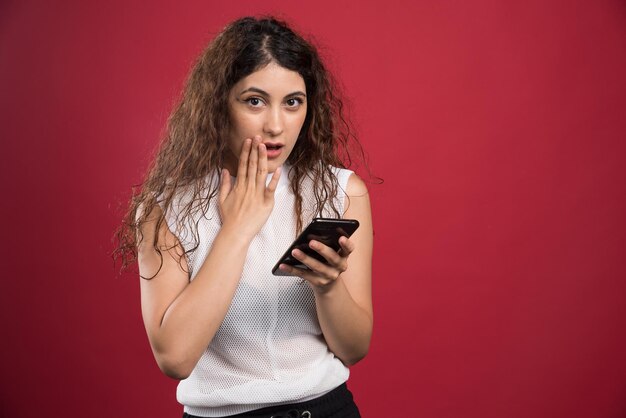 Mujer posando con teléfono en rojo