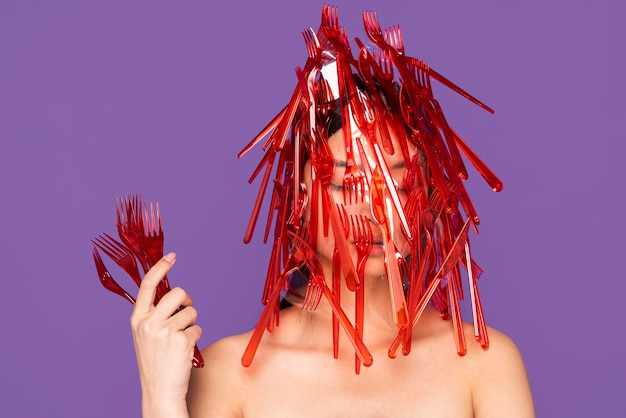 Mujer posando con vajilla de plástico rojo sobre ella